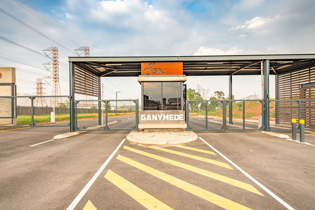 A modern commercial security gatehouse entrance featuring a steel canopy, boom gates, and secure perimeter fencing for controlled site access.