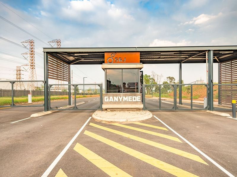 A modern commercial security gatehouse entrance featuring a steel canopy, boom gates, and secure perimeter fencing for controlled site access.