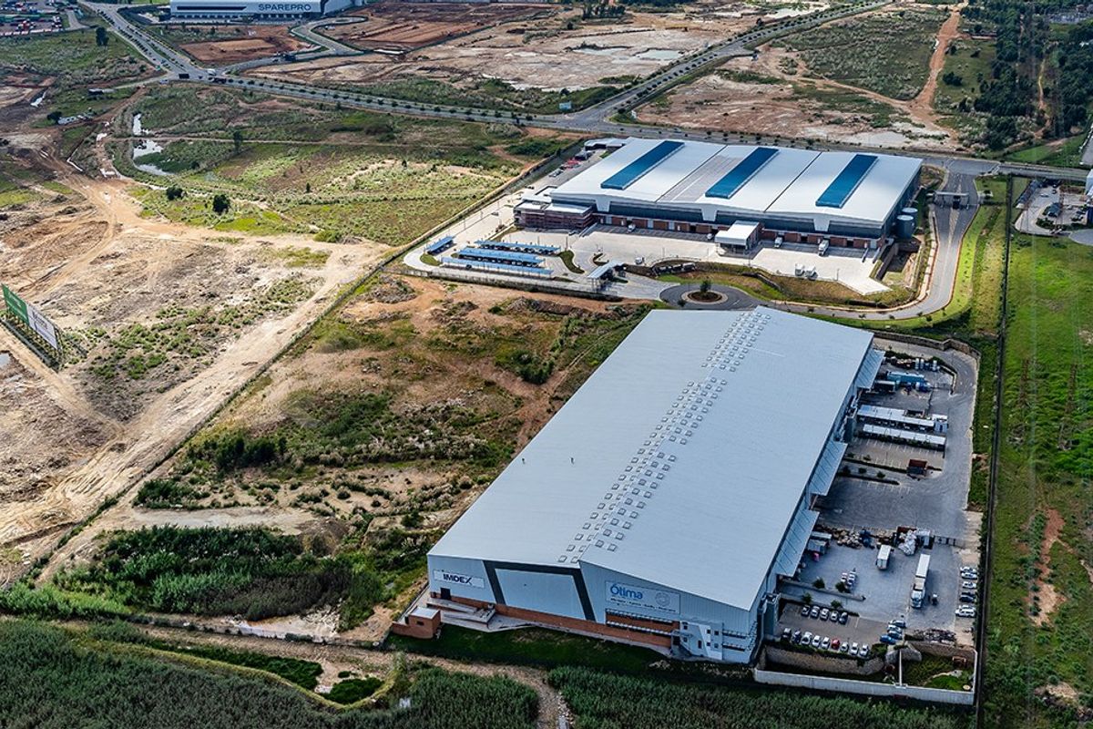 Aerial view of a large commercial industrial warehouse facility featuring extensive parking, loading bays, and surrounding landscaped grounds within an industrial park.