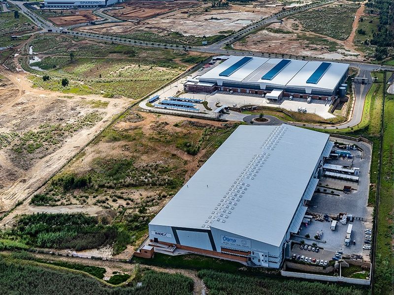Aerial view of a large commercial industrial warehouse facility featuring extensive parking, loading bays, and surrounding landscaped grounds within an industrial park.