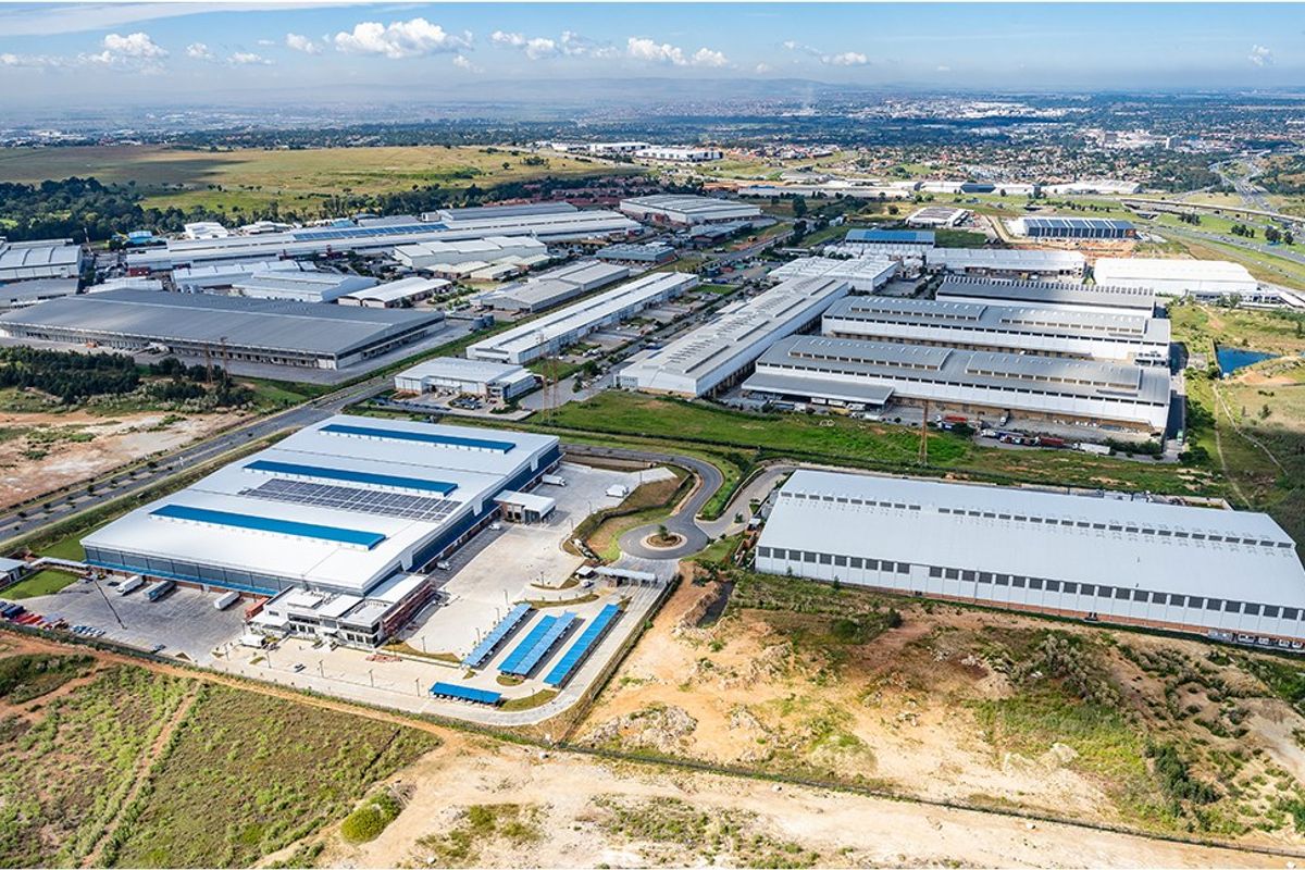 Aerial view of a large commercial industrial park featuring multiple warehouse facilities, extensive parking infrastructure, and solar energy installations.