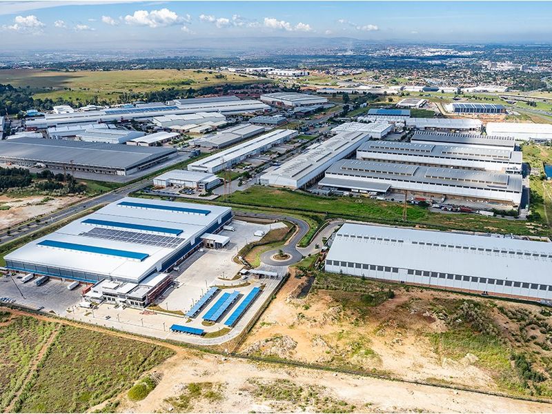 Aerial view of a large commercial industrial park featuring multiple warehouse facilities, extensive parking infrastructure, and solar energy installations.