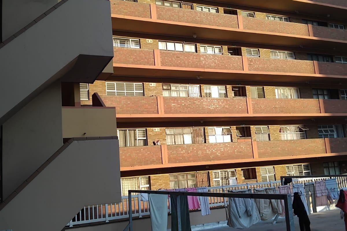 View of the apartment building exterior featuring a brick facade, external staircase, and a concrete terrace area.