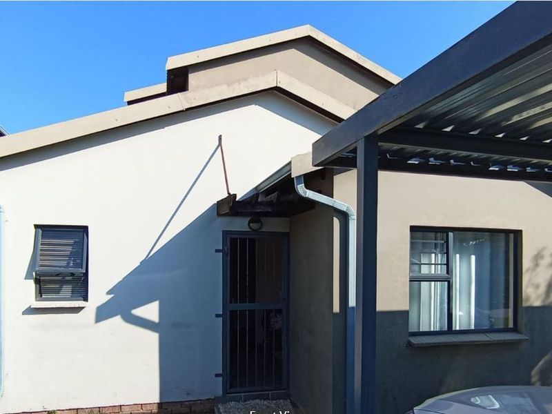 Front elevation of the house featuring a covered carport, security gate entrance, and aluminium window frames.