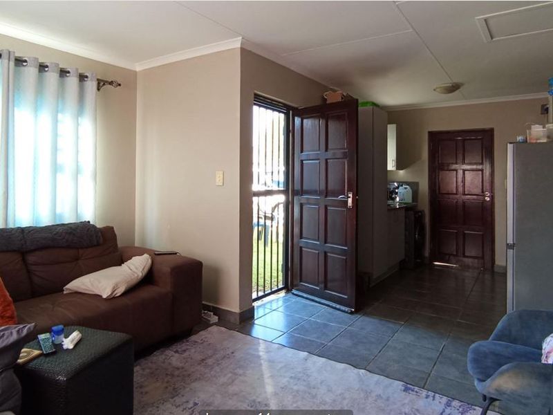 Open plan living area featuring tiled flooring, direct exterior access via a security gate, and integrated cabinetry.