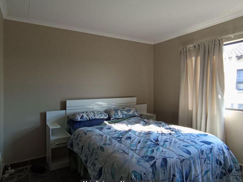 A functional bedroom featuring tiled flooring, a built-in headboard, and a window allowing natural light into the space.
