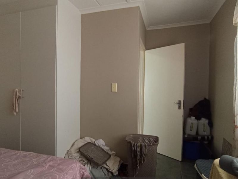 A functional bedroom featuring a built-in wardrobe and neutral wall finishes, offering a practical space with standard architectural detailing.