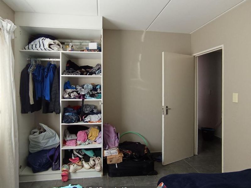 A bedroom featuring a built-in wardrobe with open shelving and tiled flooring, providing functional storage space.