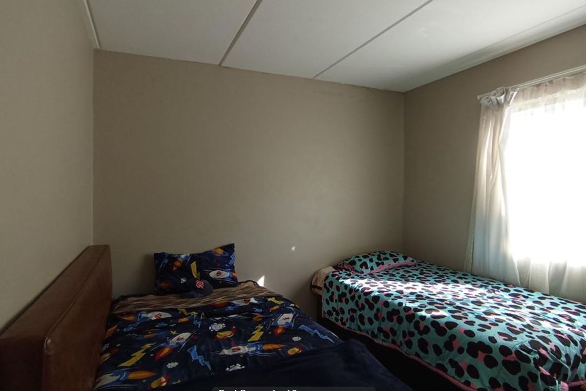A standard bedroom featuring a drop ceiling and natural light from the window.