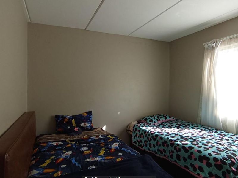 A standard bedroom featuring a drop ceiling and natural light from the window.