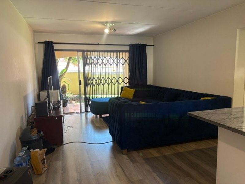 Open plan living area featuring laminate flooring and a sliding glass door with security gate leading to an outdoor space.