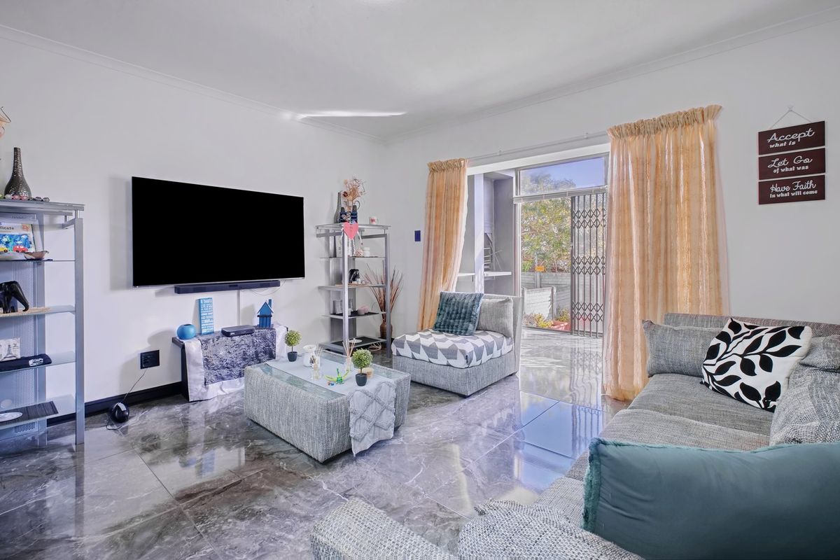 Bright living room featuring polished marble-look floor tiles and a sliding glass door providing access to the outdoor area.
