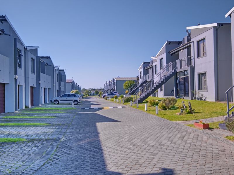 A view of the apartment complex street, featuring paved driveways, external staircases, and well-maintained building facades.