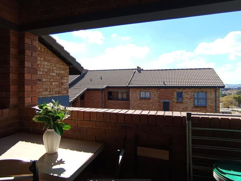 A covered balcony featuring exposed brickwork and views over the surrounding apartment complex.