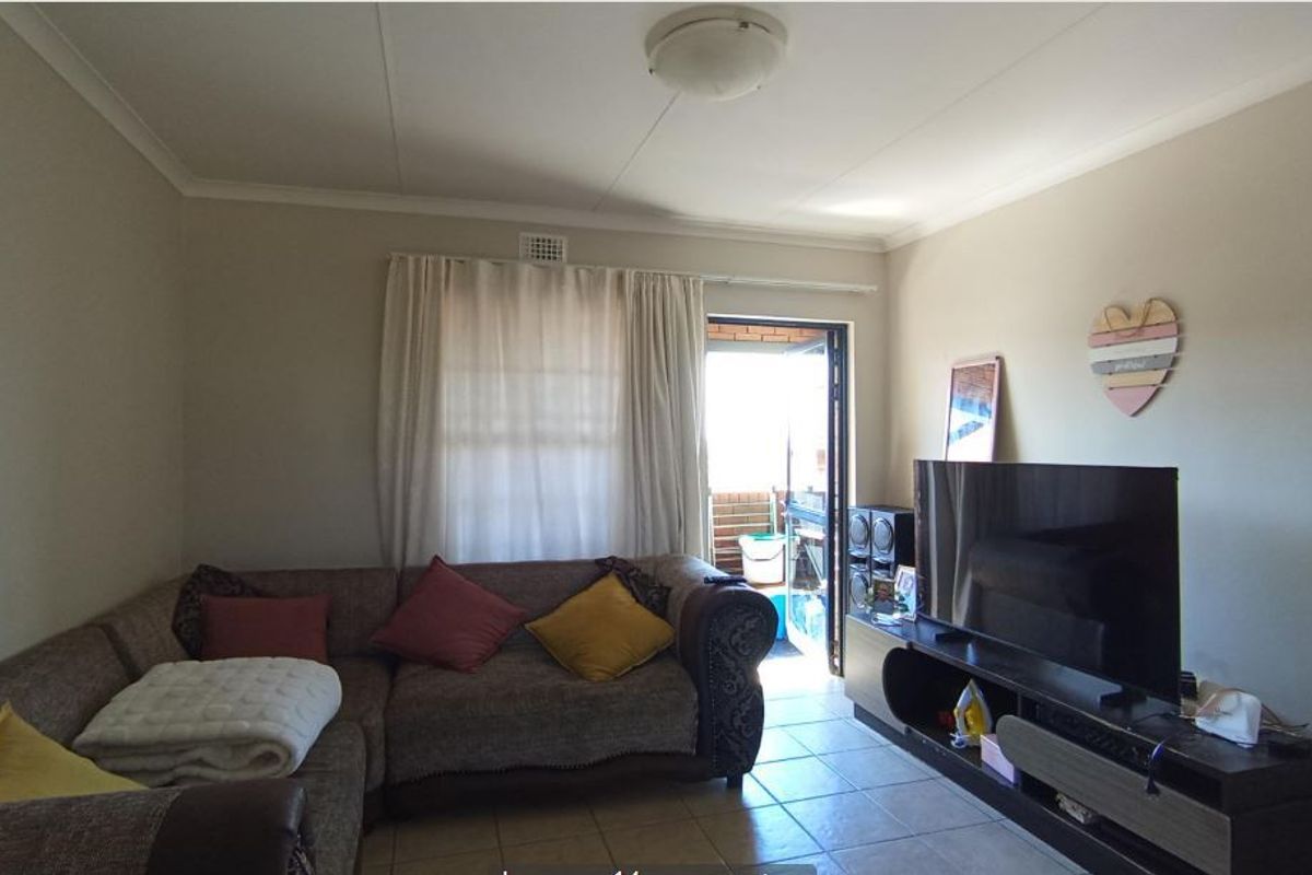 A living room featuring tiled flooring and direct access to an outdoor balcony area through a sliding door.