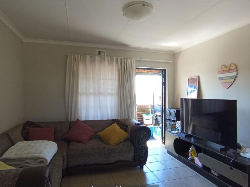 A living room featuring tiled flooring and direct access to an outdoor balcony area through a sliding door.