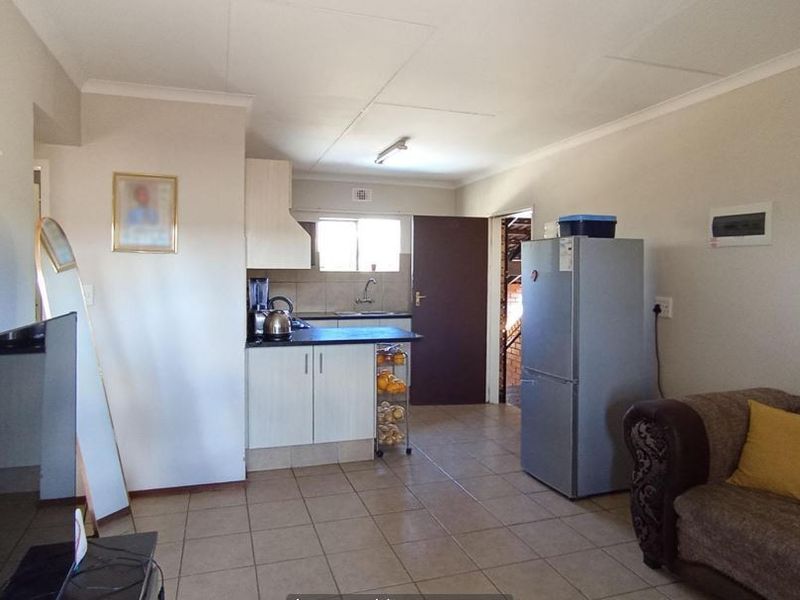 Open plan living area featuring a functional kitchen with built-in cabinetry and tiled flooring throughout the space.