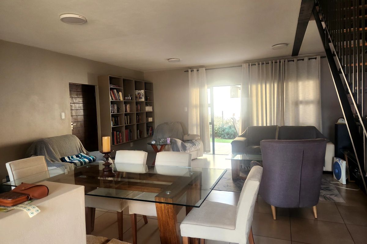 Spacious open-plan living and dining area featuring tiled floors, built-in shelving, and direct access to the outdoor space via a sliding glass door.
