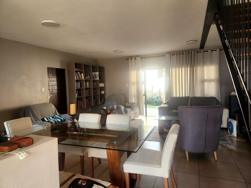 Spacious open-plan living and dining area featuring tiled floors, built-in shelving, and direct access to the outdoor space via a sliding glass door.