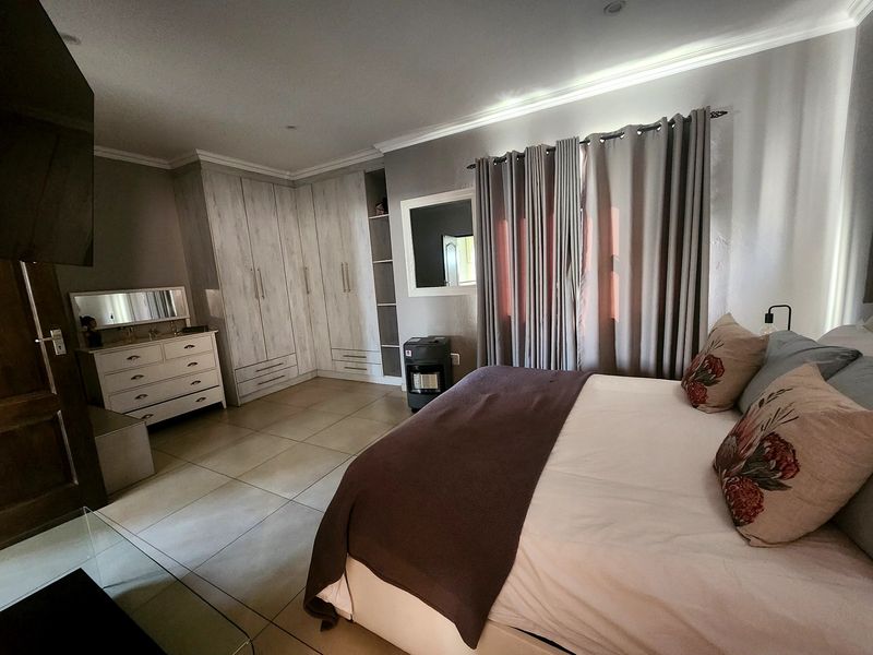 Spacious bedroom featuring neutral tiled flooring, extensive built-in cabinetry, and recessed ceiling lighting, creating a comfortable and well-maintained living space.