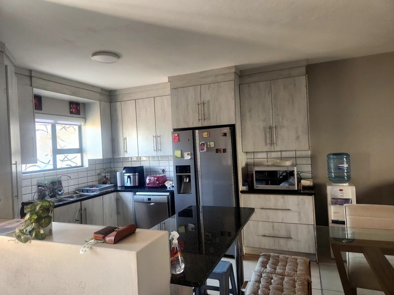 A functional kitchen featuring light-toned cabinetry, granite countertops, a breakfast bar, and a tiled backsplash, offering a practical layout for daily use.
