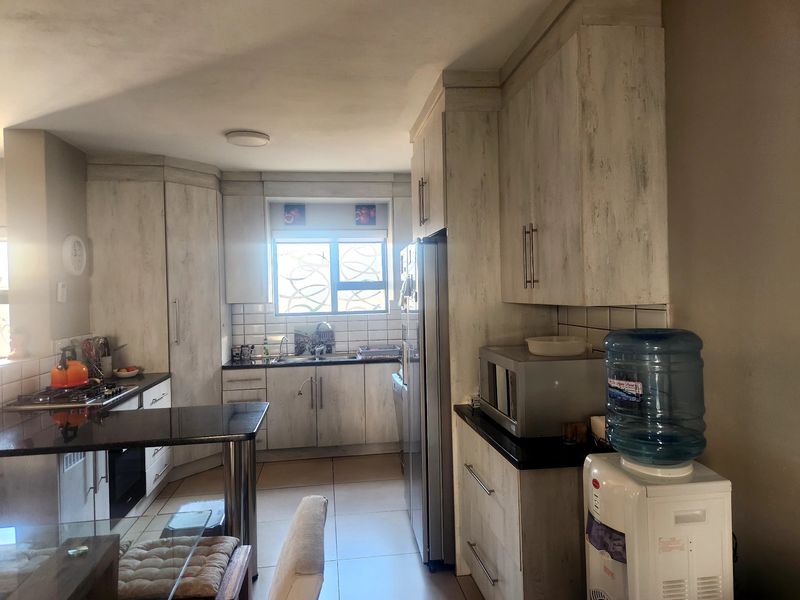 A functional kitchen featuring light-toned built-in cabinetry, dark granite countertops, a gas hob, and a built-in oven with tiled flooring and backsplash.