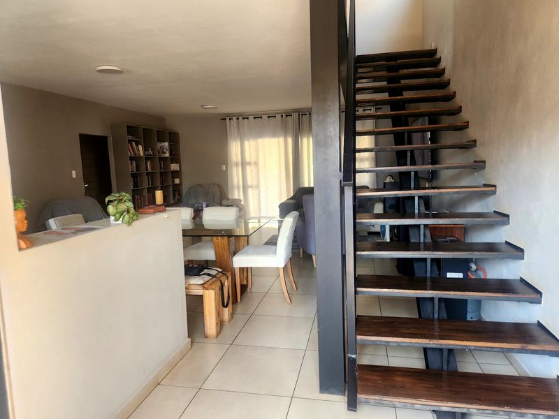 Open plan living and dining area featuring tiled flooring and a modern open-tread staircase leading to the upper level.