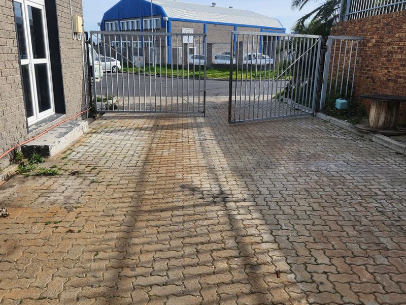 Commercial property entrance featuring a paved driveway, secure metal gates, and brick boundary walling.
