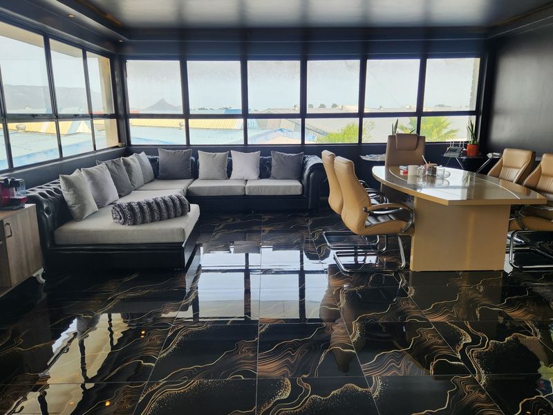 A modern, well-lit commercial office space featuring high-gloss patterned floor tiles, extensive window frontage, and integrated ceiling lighting.