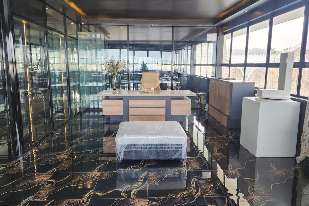 Modern executive office featuring high-end marble-effect flooring, extensive glass partitioning, and sleek built-in cabinetry with recessed ceiling lighting.