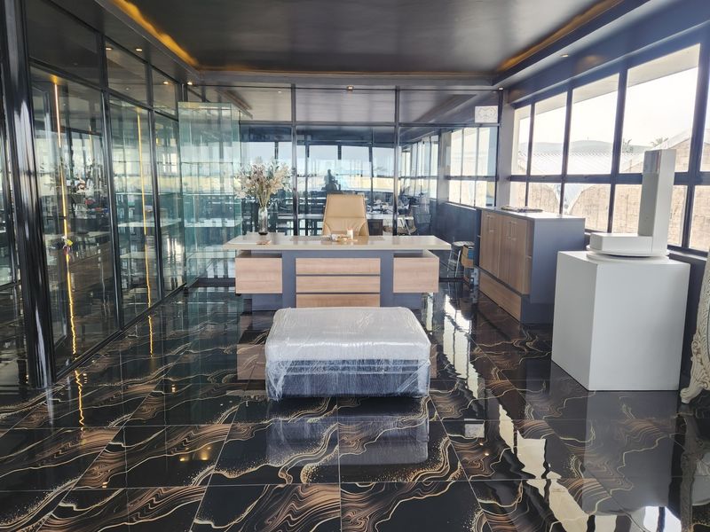 Modern executive office featuring high-end marble-effect flooring, extensive glass partitioning, and sleek built-in cabinetry with recessed ceiling lighting.
