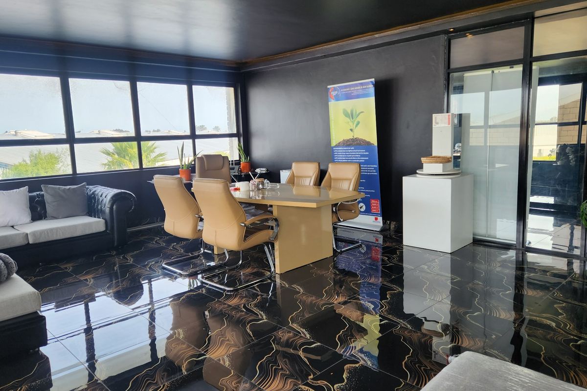 Modern office space featuring high-gloss patterned floor tiles, large windows providing natural light, and a glass partition entrance.
