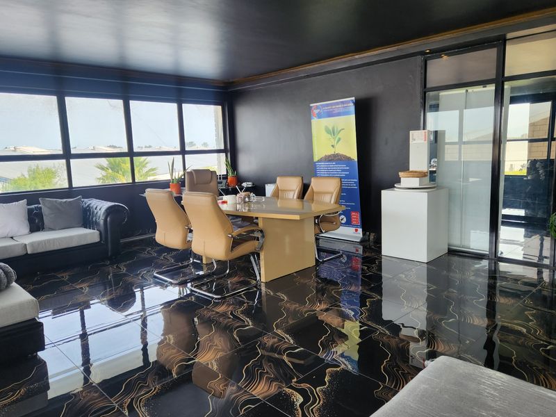 Modern office space featuring high-gloss patterned floor tiles, large windows providing natural light, and a glass partition entrance.