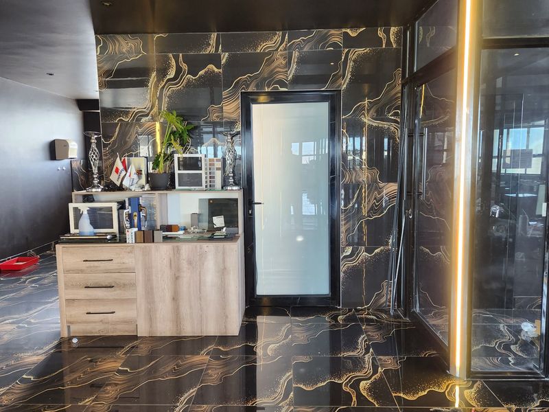 Modern commercial entry area featuring striking black and gold marble-effect floor and wall tiles, complemented by a frosted glass door and integrated LED lighting.