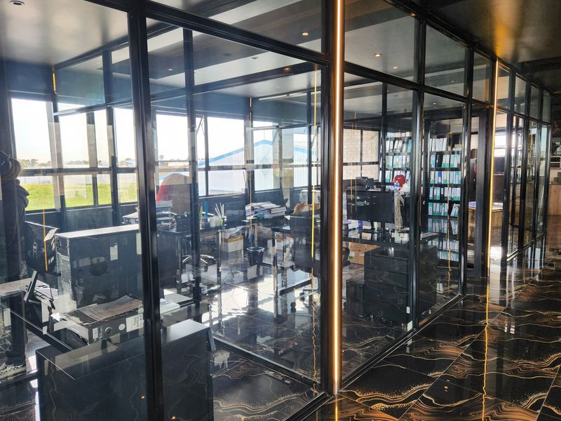 Modern commercial office space featuring sleek glass partitions, black marble-effect flooring, and integrated LED lighting, creating a professional and contemporary work environment.