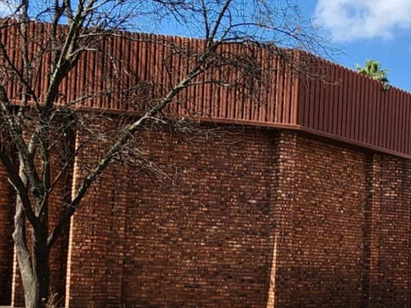 Rear exterior view of a farm building featuring traditional face brick construction and a corrugated metal roof fascia.