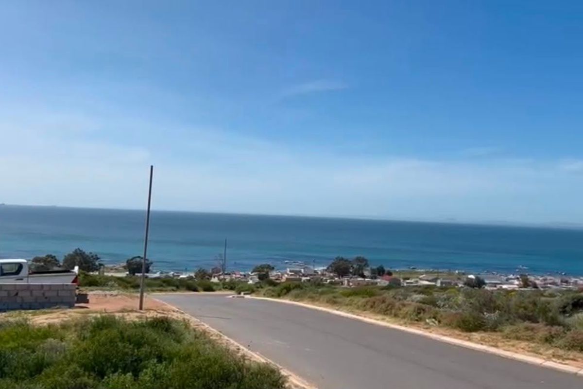 A scenic view overlooking the coastline and ocean from a paved residential street.