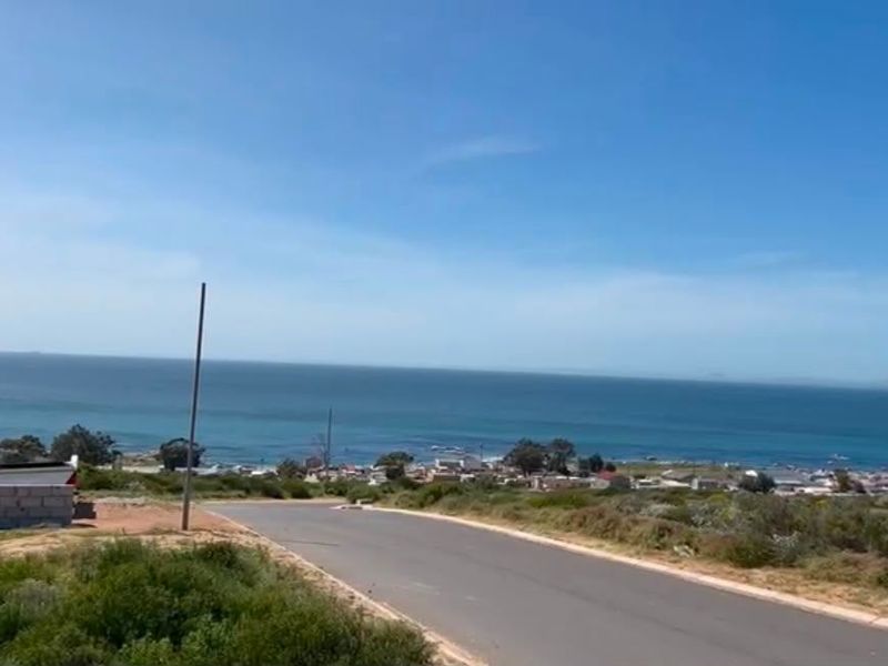 A scenic view overlooking the coastline and ocean from a paved residential street.