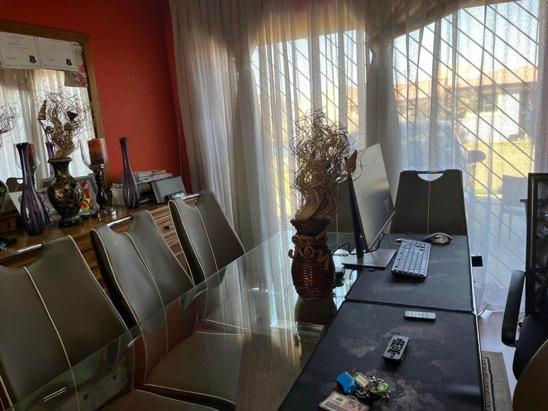 A living area featuring large windows with security gates and curtain tracks, currently utilized as a workspace.