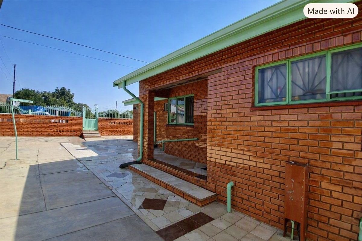 Rear exterior view of a face brick house featuring a paved courtyard, covered patio area, and perimeter walling.