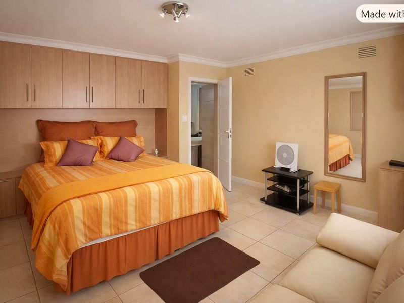 A well-maintained bedroom featuring extensive built-in cabinetry, neutral tiled flooring, and direct access to an en-suite bathroom.
