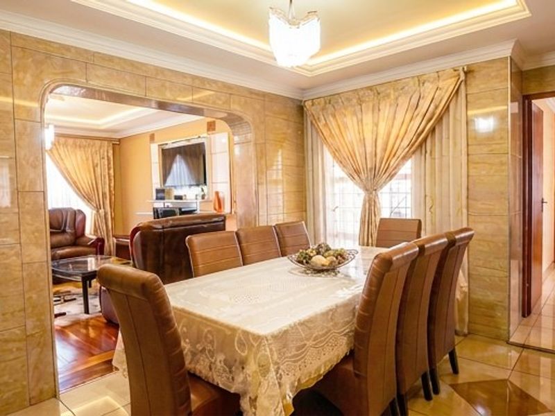Dining room featuring tiled wall finishes, recessed ceiling lighting, and an open-plan archway leading to the adjacent living area.