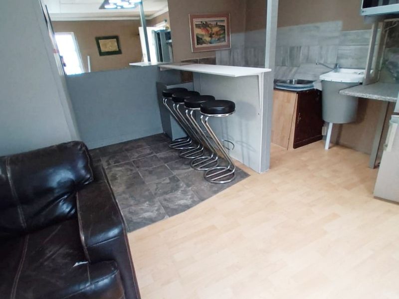 Open plan living area featuring a breakfast bar, kitchenette with built-in sink, and laminate flooring. The space offers a functional layout for casual dining.