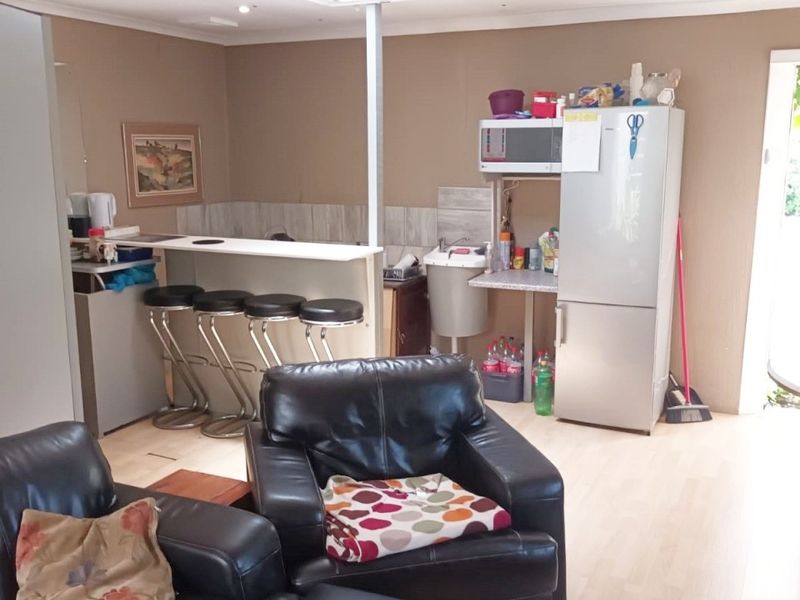Open plan living area featuring a breakfast bar, laminate flooring, and a suspended ceiling with a skylight, offering a functional layout for daily living.
