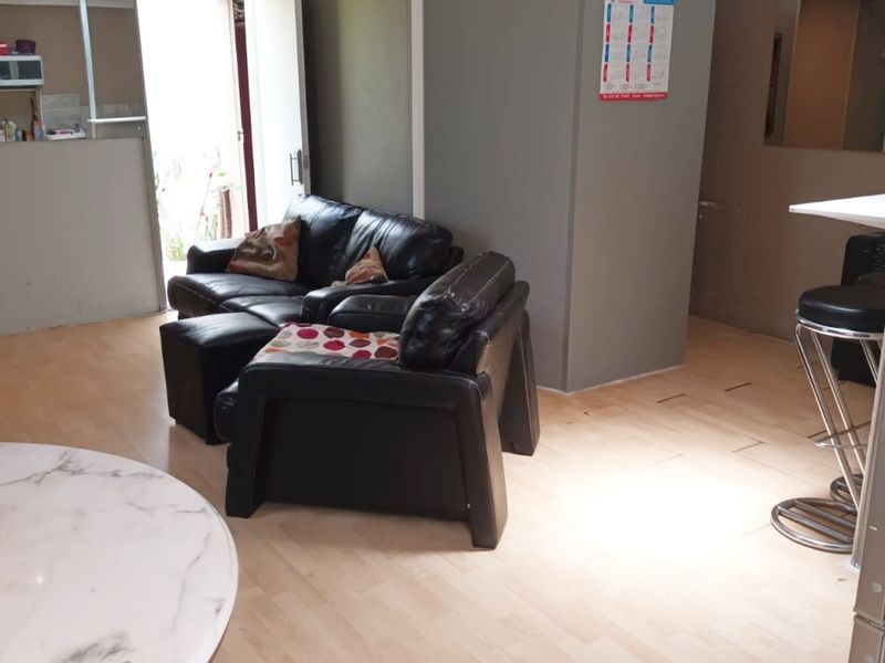 Open plan living area featuring light laminate flooring and a central partition wall, requiring ceiling and flooring finishing to improve overall presentation.