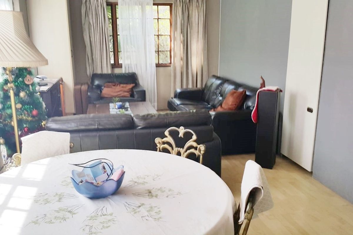 Open plan living and dining area featuring laminate flooring and timber window frames, providing a functional space for daily living.