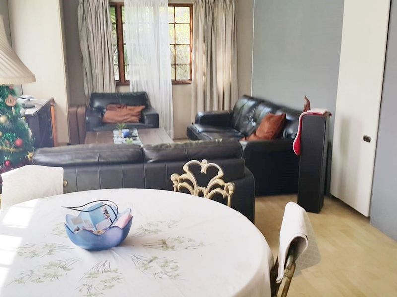 Open plan living and dining area featuring laminate flooring and timber window frames, providing a functional space for daily living.
