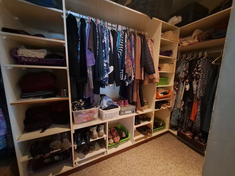 A walk-in closet featuring extensive built-in shelving and hanging rails for organized storage.