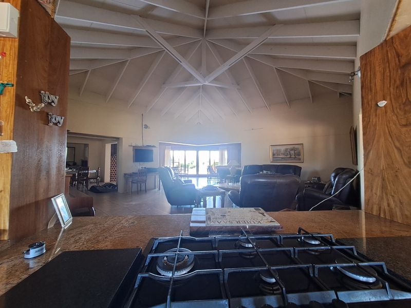 Spacious open-plan living area featuring a high vaulted ceiling with exposed beams, granite kitchen countertops, and a built-in gas hob.