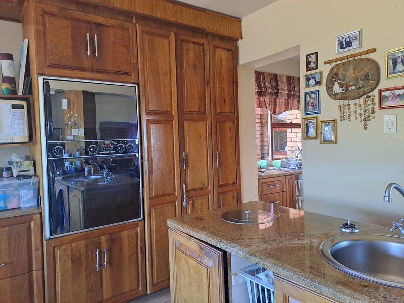 A kitchen featuring warm-toned wooden cabinetry, granite countertops, a built-in oven, and a central island with an integrated sink.